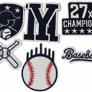 Può includere: Una collezione di toppe a tema baseball blu navy e bianche. I disegni includono uno scudo con la silhouette di un giocatore di baseball, la lettera "M", mazze incrociate, una palla da baseball, il testo "27x Champions" e la parola "Baseball".