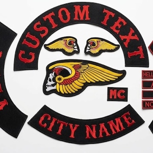 May include: A collection of black embroidered patches with red lettering. The patches include the words "CUSTOM TEXT", "CITY NAME", "AFFA", "MC", "NOMADS", "666", and "HELLS ANGELS". Several patches feature a skull with wings.