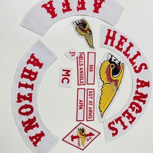 May include: A collection of white and red embroidered patches. The patches include the words "AFFA", "Arizona", and "Hells Angels" in red lettering. Several patches feature a winged skull emblem. Other patches include "MC", "666", "SGT AT ARMS", and "1% HAMC".