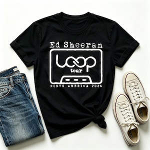 Könnte beinhalten: Ein schwarzes Kurzarm-T-Shirt mit weißem Text, der Ed Sheeran, Loop Tour und North America 2026 liest, begleitet von einer Grafik einer Kassette. Das T-Shirt wird zusammen mit einer blauen Jeans und weißen Canvas-Sneakern präsentiert.