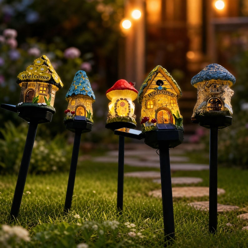 Op de afbeelding: Vijf op zonne-energie werkende tuinverlichting in de vorm van grillige huisjes en een paddenstoel. Elk heeft een ander dakontwerp en warme binnenverlichting. De eerste lamp heeft het woord "Welcome" erop. Ze staan in een grasveld.