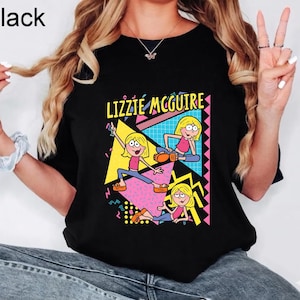 Może przedstawiać: Czarny t-shirt z nadrukiem graficznym postaci z kreskówki Lizzie McGuire w trzech różnych pozach. Projekt zawiera żółte, różowe i niebieskie geometryczne kształty, wzory oraz napis LIZZIE MCGUIRE żółtymi literami.