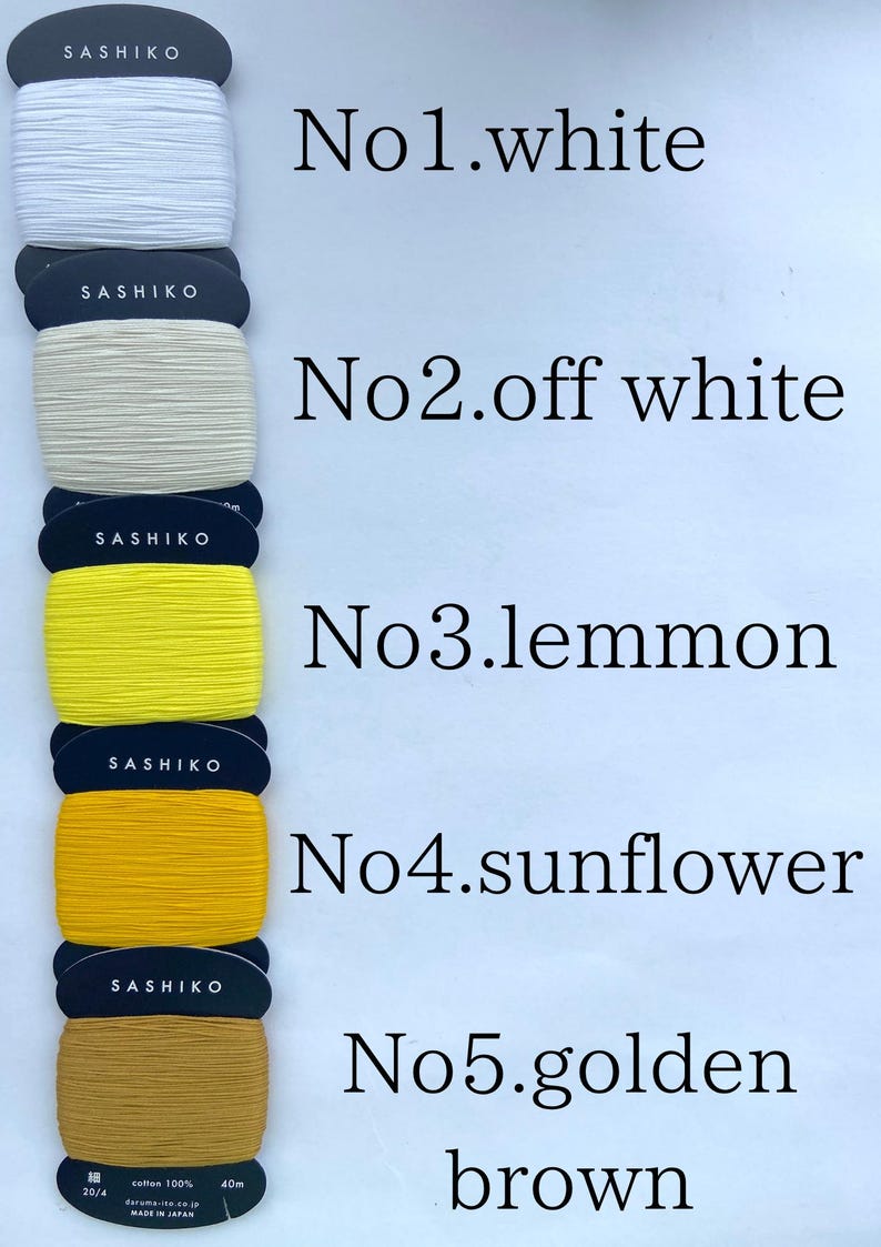 May include: Five spools of Sashiko thread wrapped on dark cards, labeled No.1 white, No.2 off white, No.3 lemmon, No.4 sunflower, and No.5 golden brown. Each spool contains 40m of 100% cotton thread, with the bottom spool showing 20/4 specifications.