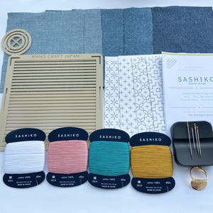 以下が含まれることがあります： ベージュのプラスチック製グリッドガイド、白、ピンク、ティール、マスタードの綿糸4巻、針入り黒色ケース、指ぬき、布地、マーキングペン、ガイドブックを含む刺し子刺繍スターターキット。