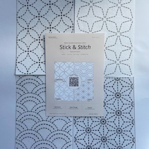 May include: Four white water-soluble embroidery sheets featuring black dashed geometric patterns, arranged around a central instruction card labelled Stick & Stitch with a QR code, text, and diagrams for peeling, stitching, and dissolving.