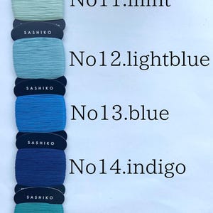 May include: Five spools of Sashiko thread wrapped on dark blue cardboard cards, labeled No11.mint, No12.lightblue, No13.blue, No14.indigo, and No15.peacock. Each spool contains 40m of 100% cotton thread, with the text Made in Japan visible.