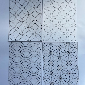 May include: Four rectangular fabric swatches featuring white backgrounds with black dashed-line patterns. The designs include interlocking circles, four-pointed stars, overlapping semicircles, and a geometric starburst pattern with central dots.