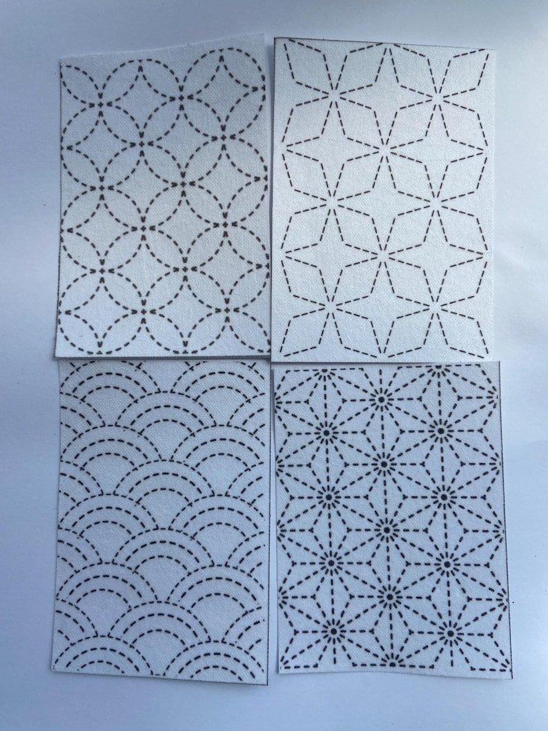 May include: Four rectangular fabric swatches featuring white backgrounds with black dashed-line patterns. The designs include interlocking circles, four-pointed stars, overlapping semicircles, and a geometric starburst pattern with central dots.