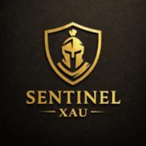 May include: A gold-colored emblem featuring a stylized Spartan helmet centered within a shield outline. Below the shield, the text reads SENTINEL XAU in a bold, serif font. The entire design is rendered in a metallic gold finish against a dark background.