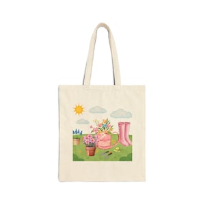May include: A cream tote bag with a garden-themed watercolour illustration. The design shows a pink watering can with flowers, pink wellington boots, potted plants, and gardening tools. A sunny sky with clouds completes the scene.