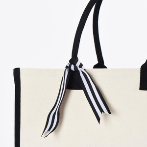 a white bag with a black and white striped bow