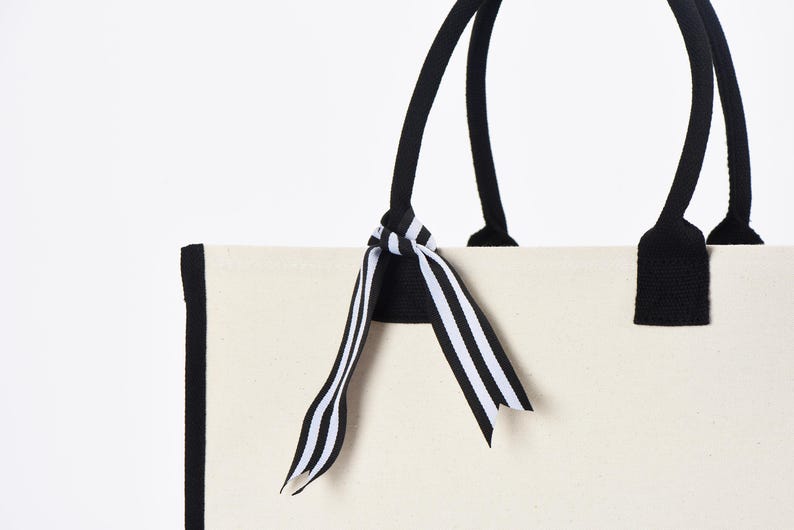 a white bag with a black and white striped bow