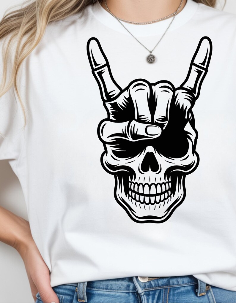 May include: A white t-shirt featuring a bold black graphic print of a human skull. The skull is depicted with a hand positioned above it, forming a rock and roll hand gesture with the index and pinky fingers extended upward.