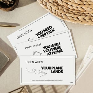 May include: A stack of white cards with black text and line drawings. The cards read "Open When" followed by phrases like "You Need a Pep Talk" and "Your Plane Lands." A special letter for moments when a text won't do.