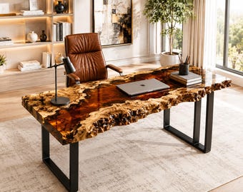 May include: A rectangular desk featuring a live-edge wood slab with a glossy amber resin inlay, supported by two black metal U-shaped legs. The desk surface holds a silver laptop, a black desk lamp, and a stack of books with a pencil holder.