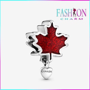 May include: A silver charm featuring a red maple leaf with a heart-shaped pendant that says "CANADA". The charm has a detailed design and is likely made of metal. The charm is a jewelry item.