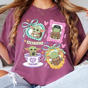 K&ouml;nnte beinhalten: Burgunderfarbenes T-Shirt mit vier gerahmten Illustrationen von Grogu, auch bekannt als Baby Yoda. Die Illustrationen zeigen Grogu in einer Teetasse, einem Rahmen und einem Pilotenhelm. Das Wort "GROGU" ist in bunten Buchstaben geschrieben.