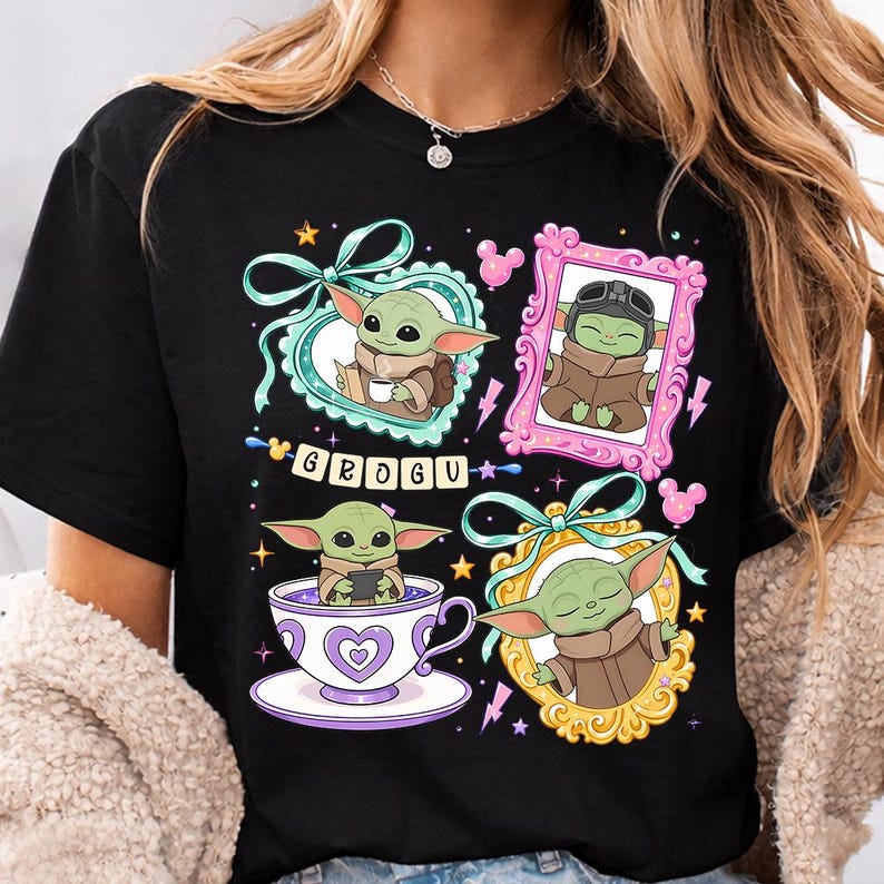 K&ouml;nnte beinhalten: Schwarzes T-Shirt mit vier gerahmten Illustrationen von Grogu, auch bekannt als Baby Yoda. Die Rahmen sind mit Schleifen, Sternen und Mickey Mouse-Silhouetten verziert. Das Wort "GROGU" ist in einer verspielten Schriftart geschrieben.