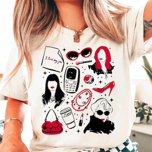 May include: White t-shirt featuring a collection of red and black illustrations. The design includes sunglasses, a high heel, a handbag, a flip phone, and the text "I love my job."
