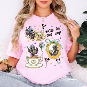 May include: Pink t-shirt featuring cartoon illustrations of characters from a popular space western series. The design includes heart-shaped frames, a teacup, and the phrase "This is Pre Way". The shirt has a crew neck and short sleeves.