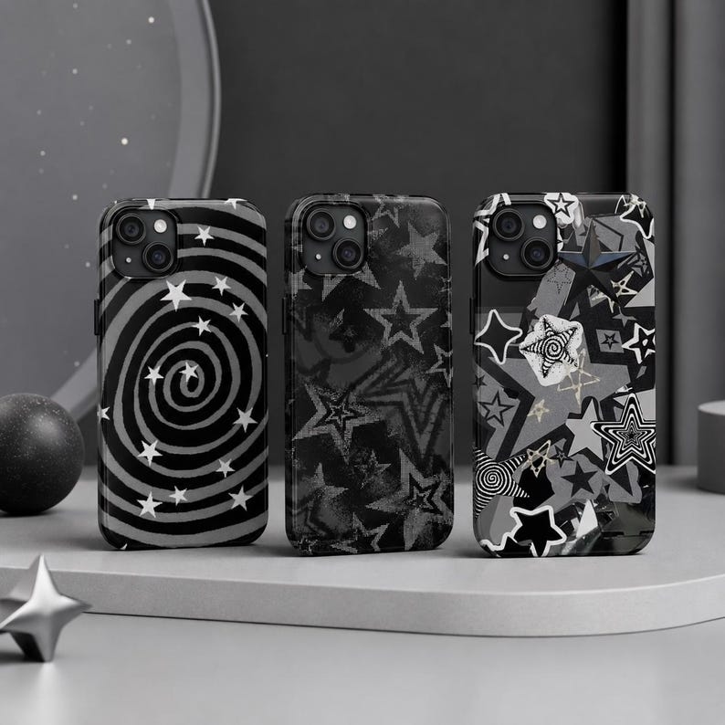 May include: Three smartphone cases featuring black, white, and grey designs. The left case has a spiral pattern with small stars. The middle case displays a textured star print. The right case shows a collage of various star shapes and patterns.
