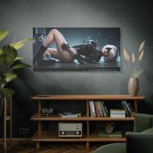Peut inclure: Impression sur toile représentant une œuvre d'art numérique d'un personnage en tenue noire avec des cheveux blancs, allongé. L'œuvre est affichée sur un mur gris foncé au-dessus d'une étagère en bois avec des livres et des objets décoratifs.
