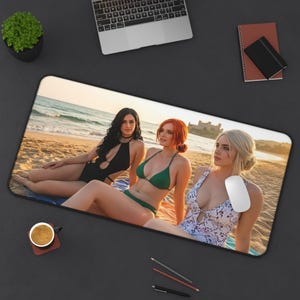 May include: Rectangular mousepad featuring a beach scene with three people in swimwear. The image shows a beach with golden sand, a blue ocean, and a castle in the background. The mousepad is designed for computer use.