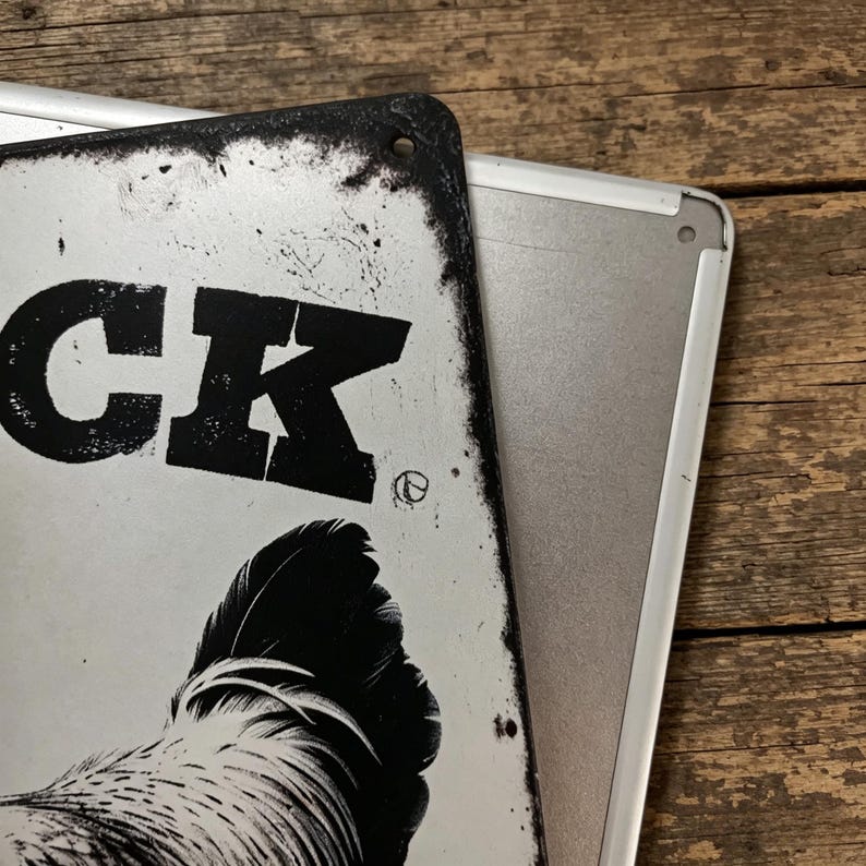 May include: Two metal signs, one partially covering the other. The top sign is white with black text that reads "CK" and a rooster illustration. The sign has a distressed, vintage look with a black border.