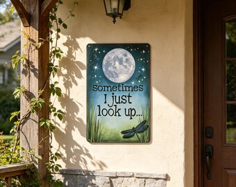 May include: A rectangular metal sign featuring a full moon, stars, and a dragonfly against a blue and green gradient background. The text reads, "sometimes I just look up..." in black lettering. The sign includes green grass at the bottom.