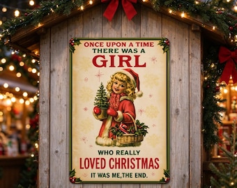 May include: A rectangular metal sign with a cream background and green border, featuring a vintage illustration of a girl in a red coat holding a small Christmas tree and basket, with the text: ONCE UPON A TIME THERE WAS A GIRL WHO REALLY LOVED CHRISTMAS IT WAS ME, THE END.