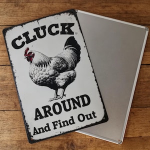 May include: A rectangular metal sign with a distressed finish. The sign features a detailed illustration of a rooster in black and white, with a red comb. The text "CLUCK AROUND And Find Out" is printed in bold, black letters.