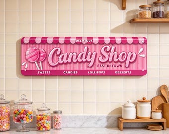 May include: A rectangular metal sign with a pink and white striped background featuring the text "Delicious Candy Shop Best In Town" and illustrations of two pink lollipops. The sign includes the words "Sweets," "Candies," "Lollipops," and "Desserts" printed in white along the bottom edge.