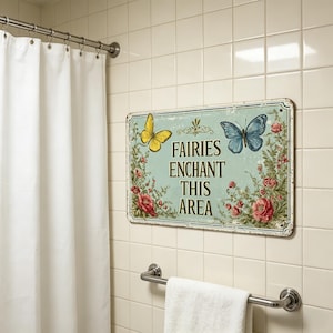 May include: A rectangular metal sign with a light blue background, featuring a yellow and a blue butterfly, surrounded by floral elements. The sign reads "FAIRIES ENCHANT THIS AREA" in brown text. The sign is mounted on a tiled wall.