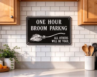 May include: A rectangular black metal sign with white text that reads ONE HOUR BROOM PARKNG and ALL OTHERS WILL BE TOAD. The sign features a white line drawing of a broom centered between the two lines of text on the black background.