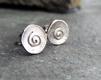 May include: A pair of silver earrings with a spiral design. The earrings are round and have a textured surface.