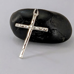 May include: A silver hammered cross pendant charm. The cross is textured and has a simple design.