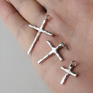 May include: Three silver cross pendants of different sizes. The crosses are textured and have a hammered finish.