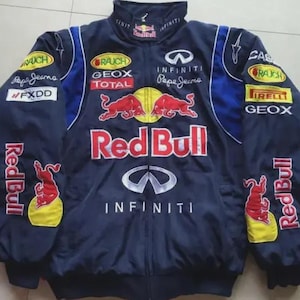 Pode incluir: Casaco de corrida azul marinho com logotipos Red Bull, Infiniti e Pepe Jeans. O casaco tem gola alta, fecho de correr e patches com vários logotipos de marcas. As mangas têm detalhes amarelos e azuis. Roupa de desporto automóvel.