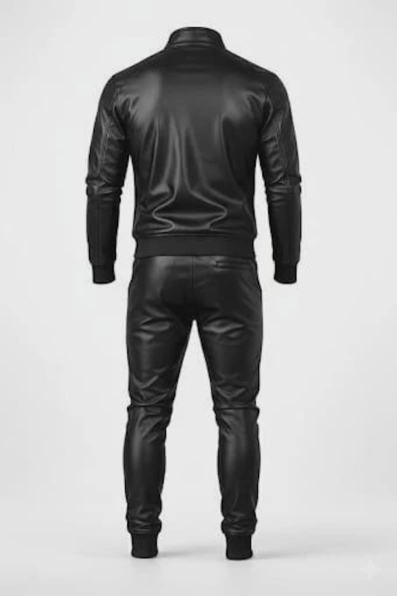 May include: A black leather tracksuit, consisting of a zip-up jacket and matching pants. The jacket has a stand-up collar and ribbed cuffs and hem. The pants have a jogger style with ribbed cuffs. The outfit is made of a shiny, faux leather material.