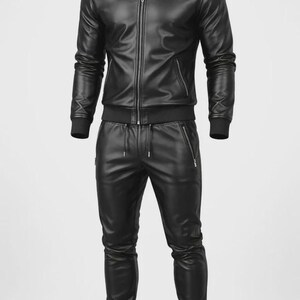 May include: A black leather tracksuit featuring a zip-up jacket with a stand-up collar and matching pants. The jacket has a front zipper closure and side pockets. The pants have a drawstring waist and zippered pockets. The outfit is made of a smooth, shiny material.