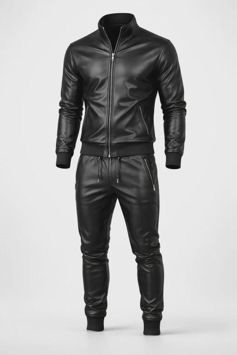 May include: A black leather tracksuit featuring a zip-up jacket with a stand-up collar and matching pants. The jacket has a front zipper closure and side pockets. The pants have a drawstring waist and zippered pockets. The outfit is made of a smooth, shiny material.