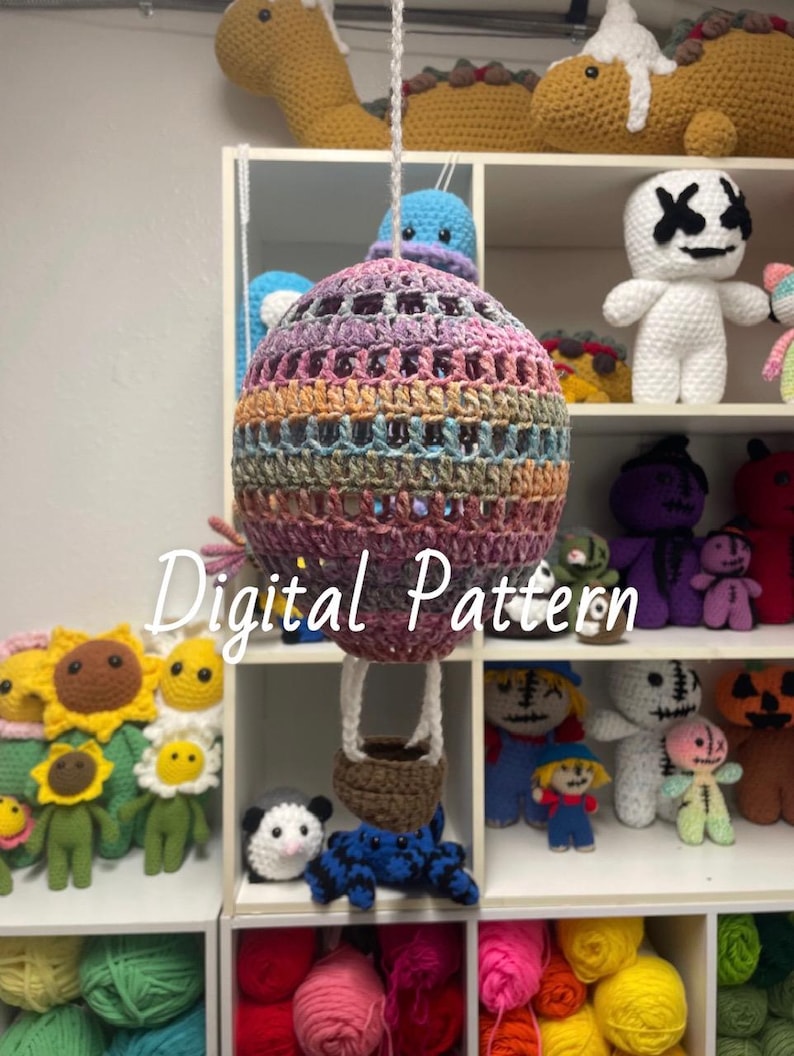 May include: A crochet hot air balloon pattern with a rainbow color scheme. The pattern is digital and includes instructions for crocheting the balloon, basket, and strings. The image shows the finished product, which is a colorful and whimsical hot air balloon.