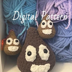 Op de afbeelding: Digitaal patroon voor het haken van een bruine poep-emoji met een witte glimlach en ogen. Het patroon wordt getoond op een plank met twee andere gehaakte poep-emojis, een bruine en een lichtbruine, en twee bollen garen, een blauwe en een paarse.