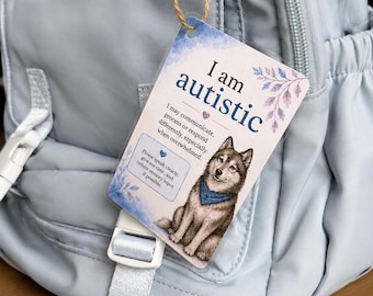 May include: A rectangular tag hanging from a light blue backpack. The tag features the text I am autistic, a drawing of a dog wearing a blue bandana, and text explaining communication needs. The design includes blue and purple floral accents.