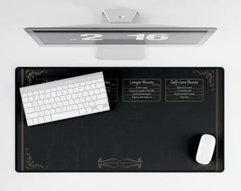 May include: A black desk mat featuring gold decorative corners and text boxes labelled Longer Boosts and Self-care Boosts. A white wireless keyboard and a white computer mouse are placed on the mat, which sits below a computer monitor displaying 2:16.