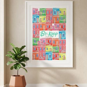 Può includere: Una stampa incorniciata ad acquerello con case colorate a Bo-Kaap, Sudafrica. Le case sono dipinte in vivaci tonalità di rosso, blu, verde e giallo. La stampa include il testo "Bo-Kaap South Africa" in verde acqua.
