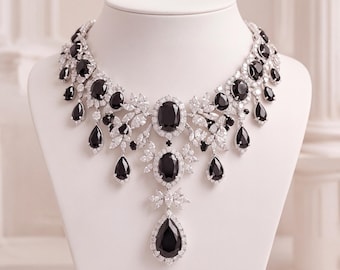 Könnte beinhalten: Ein auffälliges Collier mit mehreren ovalen und birnenförmigen schwarzen Steinen in silberfarbener Fassung. Das Design umfasst zahlreiche klare, marquise- und rundgeschliffene Steine, die die schwarzen Edelsteine in einem floralen Muster umgeben.