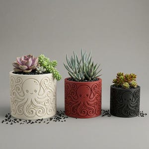 May include: Three cylindrical planters in white, red, and black, each featuring a debossed octopus design with swirling tentacles. The white planter holds a large succulent, the red planter contains spiky plants, and the black planter holds small succulents.