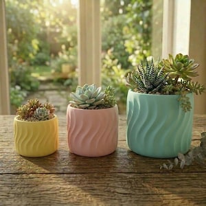 May include: Three ceramic planters in yellow, pink, and teal, each with a wavy design and filled with succulents. The planters are arranged on a wooden surface, with a bright, natural background.