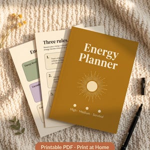 Puede incluir: Cuaderno "Energy Planner" de color mostaza con un dise&ntilde;o de sol y el texto "High - Medium - Survival". El planificador est&aacute; junto a dos p&aacute;ginas con texto y un bol&iacute;grafo negro. Las palabras "Printable PDF - Print at Home" est&aacute;n en la parte inferior.